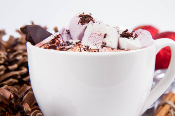 Cup of hot chocolate with marshmallows, and some cinnamon sticks, cones, christmas balls and candles	