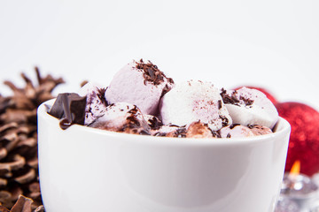 Cup of hot chocolate with marshmallows, and some cinnamon sticks, cones, christmas balls and candles	