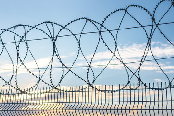 Barbed wire against the sky. Fencing at customs. Penetration protection. Safety methods. Forbidden entry. Steel mesh as a barrier. Fence as a jailbreak warning.