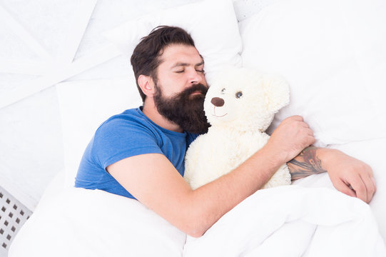 Sweet dreams. Bearded hipster play toy. Valentines day gift. Man sleep hug soft toy relaxing in bed. Cute teddy bear toy. Softness tenderness. Playful adult fall asleep. Good night. Sleep well
