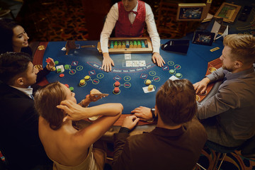 Group of people gambling sitting at a table in a casino top view