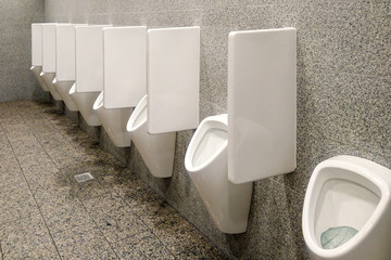 public toilet with gray walls and many white urinals