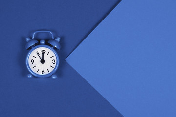 Blue alarm clock on trendy toned background.