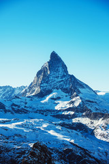 Malerischer Blick auf den schneebedeckten Gipfel des Matterhorns an sonnigen Tagen mit blauem Himmel, Zermatt, Schweiz. Schöner Naturhintergrund der Schweizer Winteralpen mit Schnee bedeckt. Berühmtes Reiseziel.
