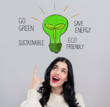 Green light bulb with happy young woman on a gray background