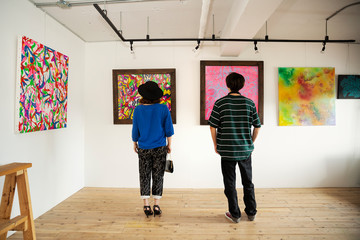 Rear view of Japanese man and woman looking at abstract painting in an art gallery.