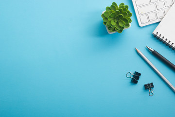 Blue desk office with laptop, smartphone and other work supplies with cup of coffee. Top view with...