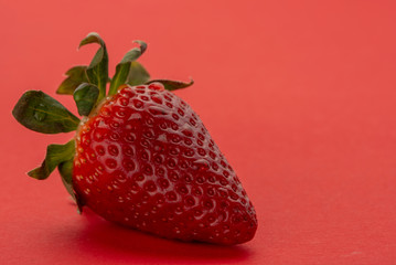  This fresh strawberry is on a red background.