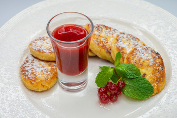 These are curd pancakes with cranberry jam on a white dish