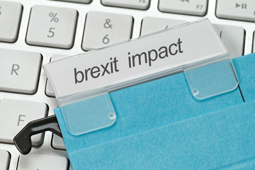 blue hanging file with the term brexit impact on a computer keyboard