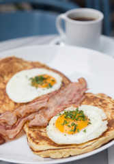 Breakfast with bacon, eggs, pancakes and coffee on white marble table
