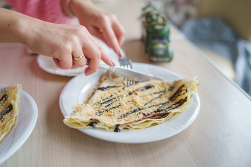 High angle close up on female woman cutting the sweet pancake in the plate on the table hands...