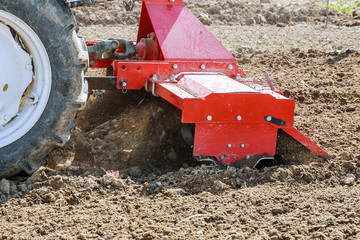 Farmer plows the field. Small tractor with a plow in the field. Cultivation.