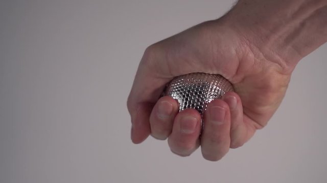 A young man breaks a silver Christmas ball. Slow motion. The concept of a bad start to the year