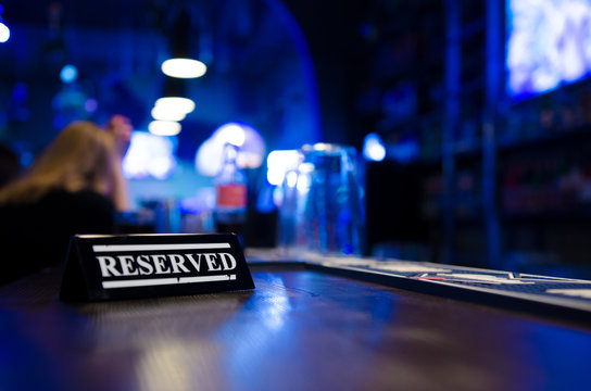 Restaurant reserved table sign standing on wooden table in bar