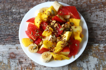 Selective focus. Fresh juicy fruit salad on a plate with mango, grapefruit and seeds. Healthy food. Vegan diet.