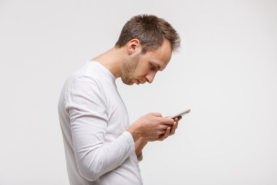 Close up portrait of man looking and using smart phone with scoliosis, side view, isolated on gray background. Rachiocampsis, kyphosis curvature of neck, Incorrect posture, ,  orthopedics concept