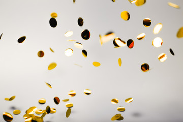 Golden falling confetti on grey background. Holiday concept.