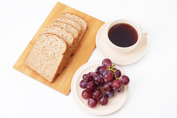 Whole grain bread and grapes serve with a cup of coffee..