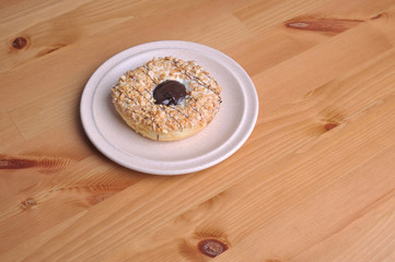 A donut with peanut as a topping on top of wooden table.