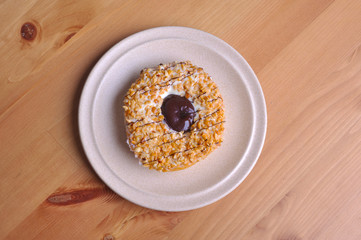 A donut with peanut as a topping on top of wooden table.