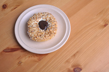 A donut with peanut as a topping on top of wooden table.