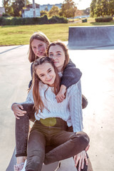 3 girlfriends girls, happy sit and smile, teenagers after school, relax ride skateboard, afternoon city, rejoice have fun. Emotions of relaxation entertainment, casual wear sneakers jeans in sweater.