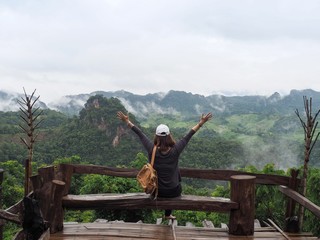 A girl / woman / lady is relaxing with beautiful view of cloudy morning at the scenic area in a community-based tourism (CBT) village of Mae Hong Son province, Thailand.