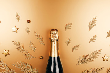 Golden Champagne bottle with parts of fir tree. Flat lay style. Holiday concept.