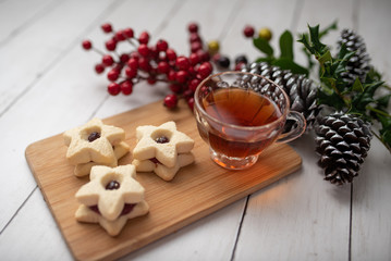 Christmas shortbread star cookies with strawberry jam. Festive atmosphere holiday pastry baking concept. Cookies and tea for Santa