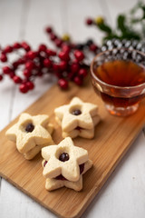 Christmas shortbread star cookies with strawberry jam. Festive atmosphere holiday pastry baking concept. Cookies and tea for Santa