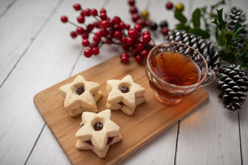 Christmas shortbread star cookies with strawberry jam. Festive atmosphere holiday pastry baking concept. Cookies and tea for Santa