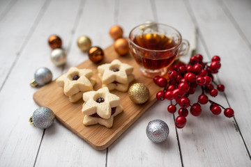 Christmas shortbread star cookies with strawberry jam. Festive atmosphere holiday pastry baking concept. Cookies and tea for Santa