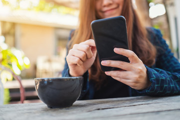 Closeup image of a woman holding and touching on mobile phone screen