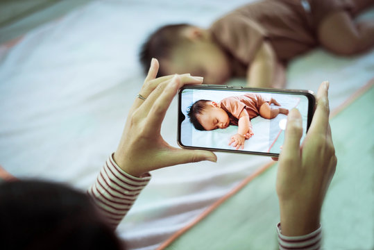 Mother hands taking a picture to baby boy with smart phone,Family memory concept,Close up