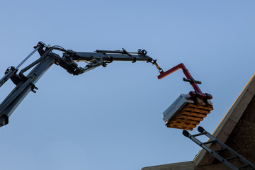 Heavy boom truck machinery is used to add the roof trusses to a timber frame house extension