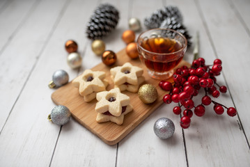Christmas shortbread star cookies with strawberry jam. Festive atmosphere holiday pastry baking concept. Cookies and tea for Santa