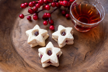 Christmas shortbread star cookies with strawberry jam. Festive atmosphere holiday pastry baking concept. Cookies and tea for Santa