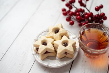 Christmas shortbread star cookies with strawberry jam. Festive atmosphere holiday pastry baking concept. Cookies and tea for Santa
