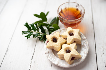 Christmas shortbread star cookies with strawberry jam. Festive atmosphere holiday pastry baking concept. Cookies and tea for Santa