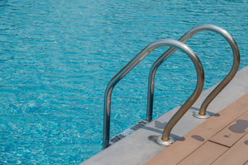 Stairs Ladder and handle down the swimming pool with blue water