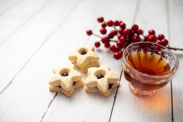 Christmas shortbread star cookies with strawberry jam. Festive atmosphere holiday pastry baking concept. Cookies and tea for Santa