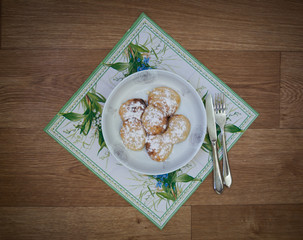 Traditional Slav cheesecakes  on a white plate with sugar powder. Cheesecakes on the plate decorated with beautiful napkin and cutlery on the wooden background. Top view
