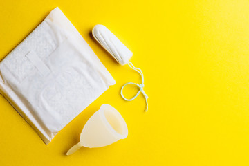 Pad, menstrual cup, tampon on yellow background. Alternative feminine hygiene product during the period. Women health concept. Flat lay. Copy space.
