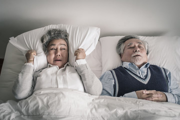 elderly couple caucasian senior woman and man sleep on bed and snoring in white blanket in bedroom,...