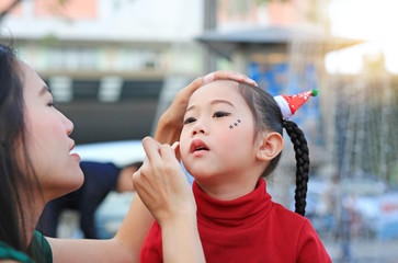 Mother applying makeup on her daughter face.