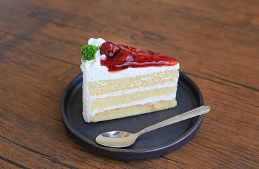 Strawberry cake in metal tray with spoon on wooden table.