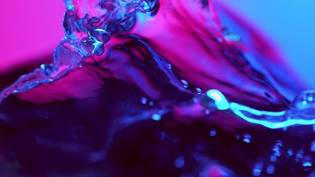 Super slow motion of splashing water wave illuminated by neon lights. Filmed on very high speed camera, 1000 fps.
