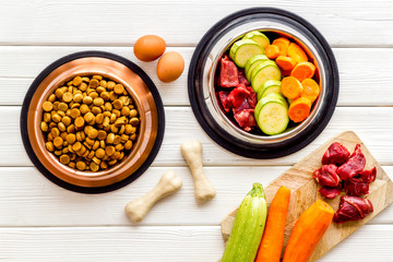 Ingredients of dry feed for dogs - meat, vegetables - near bones on white wooden background top-down