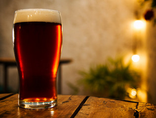 Fresh foamy shiny red beer on the bars table in a hot night